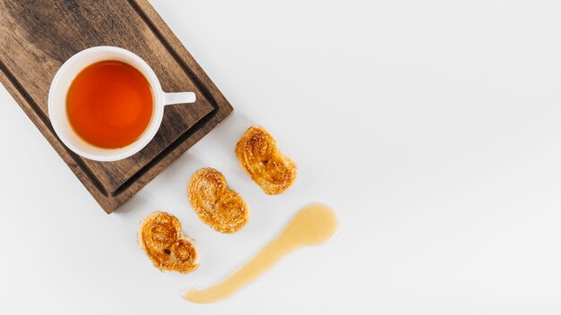 High angle view of tea near palmier biscuits and honey on white background