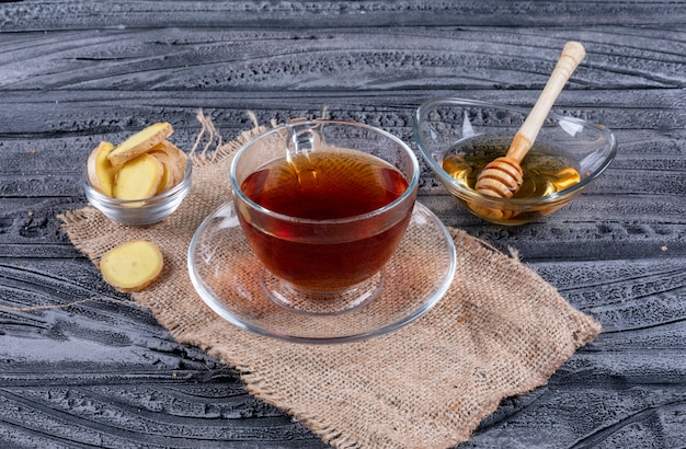 ハイアングルは、生姜と蜂蜜入りのお茶を袋の布と暗い背景の木に表示します。横型