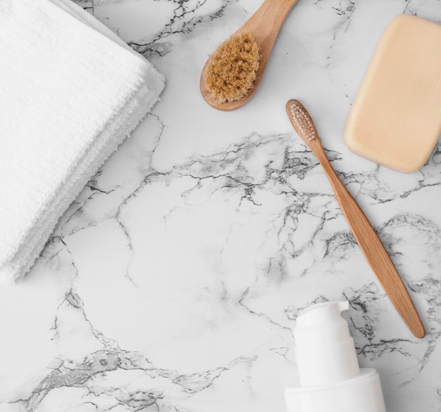 High angle view of towels; brush; soap and cosmetic bottle on marble surface