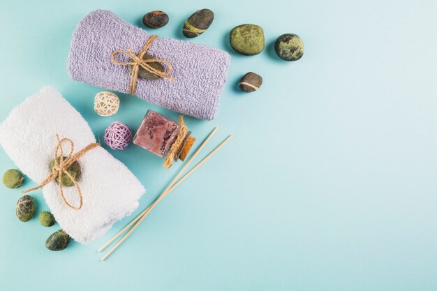 High angle view of towels; scrub bottle and spa stones on blue background