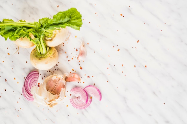 High angle view of turnip; onion slice and garlic cloves background