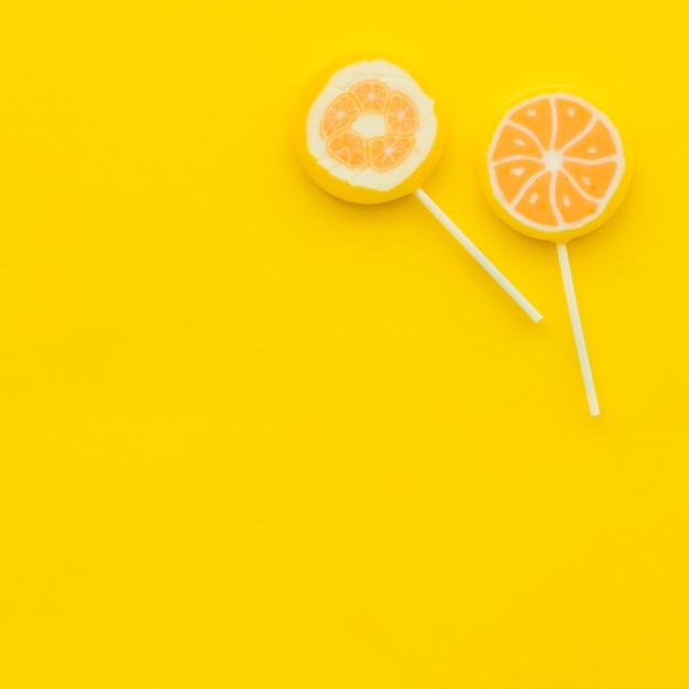 High angle view of two citrus lollipops on yellow backdrop