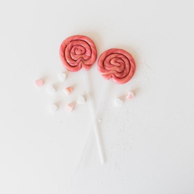 Free photo high angle view of two lollipops with heart shape candies