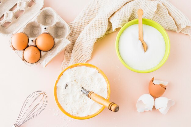 High angle view of various baking ingredients on colored background
