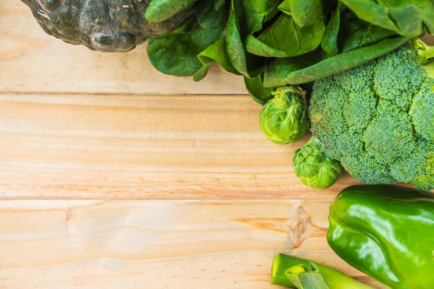 High angle view of various fresh green vegetables on wooden background