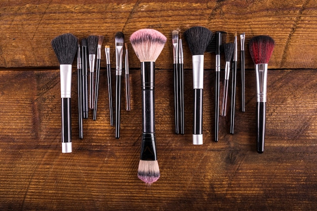 High angle view of various makeup brushes on wooden backdrop