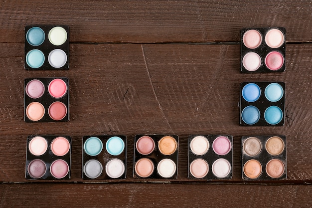 High angle view of a various multi colored eyeshadow powder on wooden background