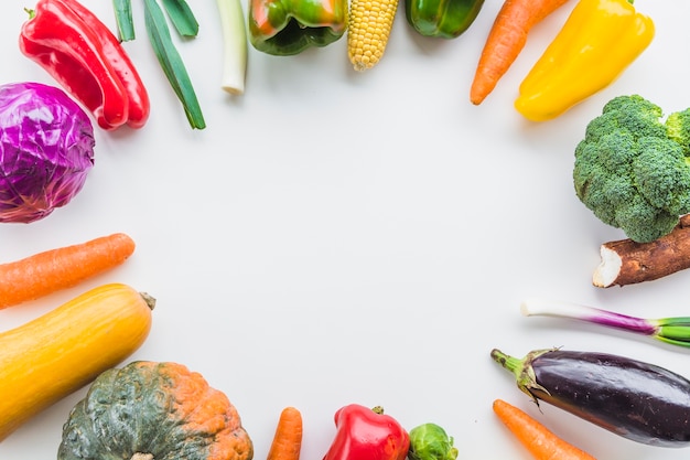 High angle view of various raw vegetables forming circular frame on white background