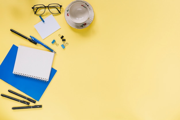 High angle view of various stationeries and cup on yellow background