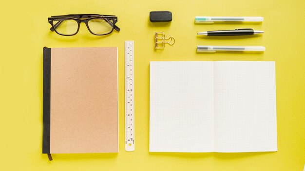 High angle view of various stationeries on yellow backdrop