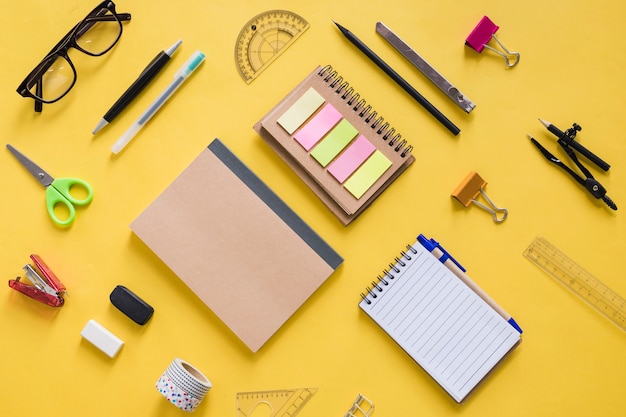 High angle view of various stationeries on yellow surface