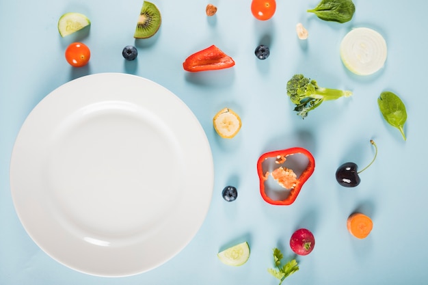 Free photo high angle view of vegetables and plate on blue background