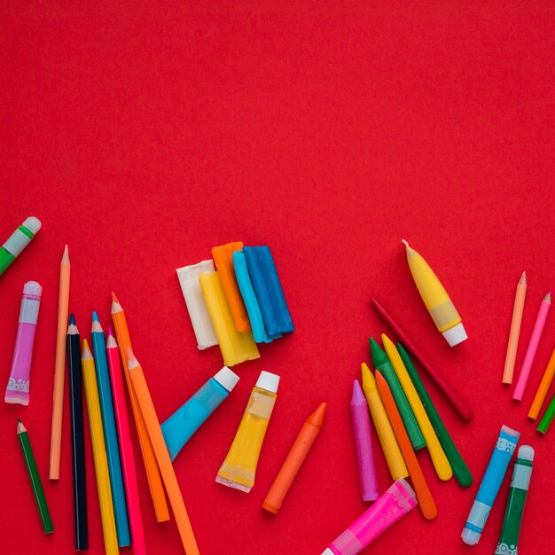 High angle view of vivid painting colors over red backdrop