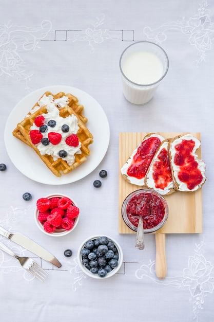 High angle view of waffles with berry fruits and milk