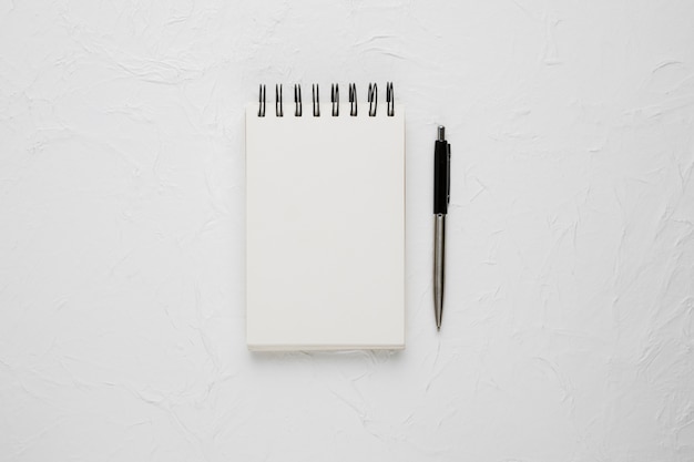 High angle view of a white blank spiral notepad with ballpoint pen