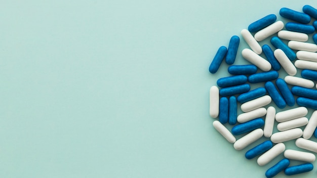 High angle view of white and blue candy capsules on green background