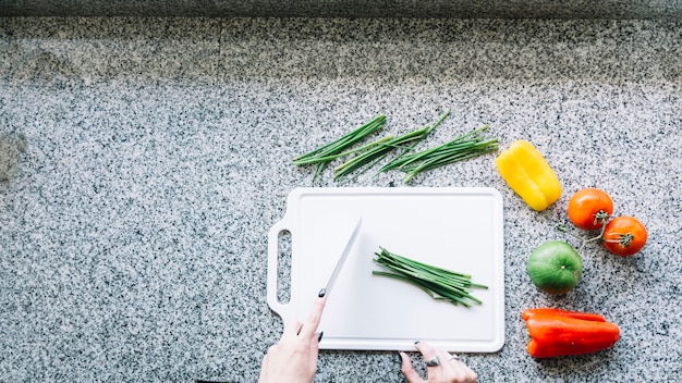 High angle view of woman's hand cutting vegetables on chopping board