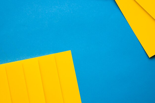 High angle view of yellow cardboard papers on blue backdrop