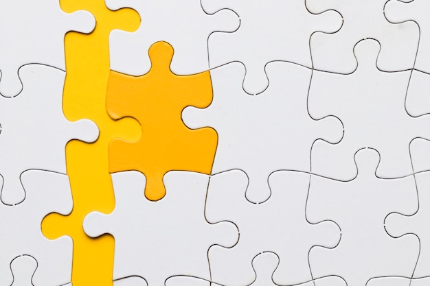 High angle view of yellow puzzle piece arranged with white pieces