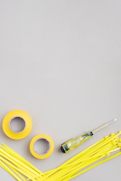 High angle view of yellow tape and nylon zip wire with electrical tester screwdrivers