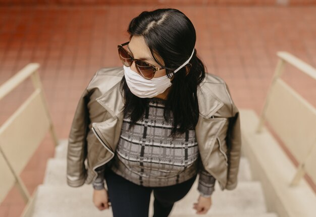 High angle view of a young Hispanic female with sunglasses wearing a facemask