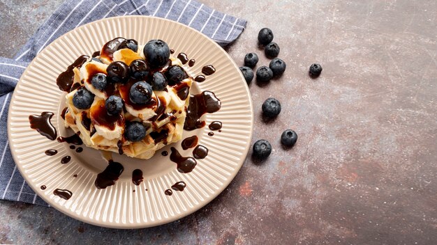 High angle of waffles covered in blueberries and topped with chocolate sauce