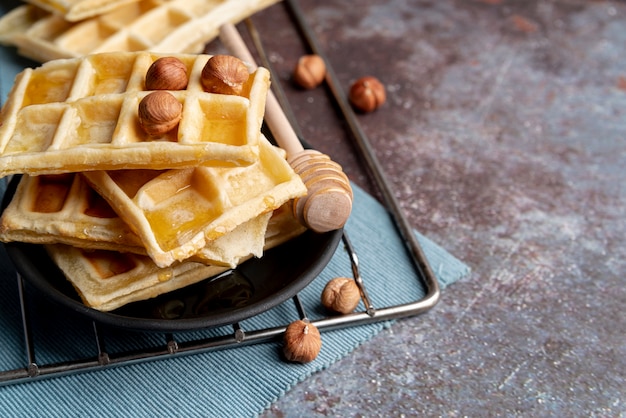 High angle of waffles on plate with hazelnuts and honey dipper