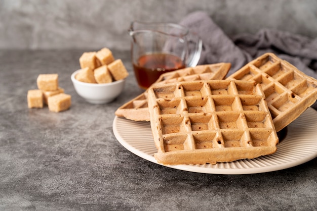 High angle of waffles on plate with sugar cubes and syrup