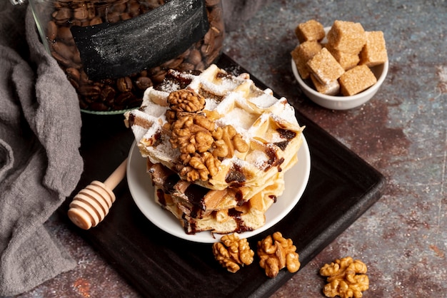 High angle of waffles stacked on plate with walnuts and sugar cubes