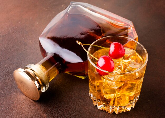 High angle whiskey glass and cherries with bottle