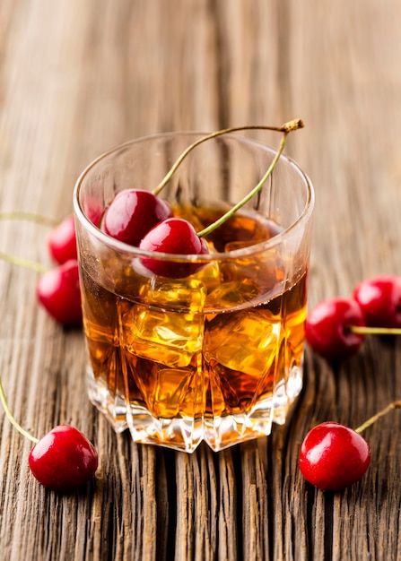 High angle whiskey glass with ice and cherries