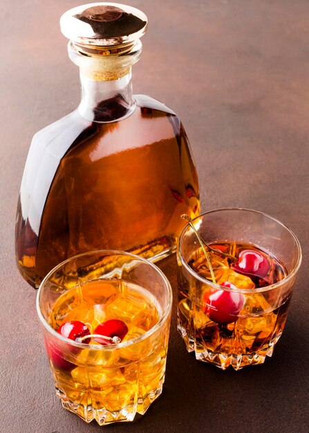 High angle whiskey on the rocks with cherries and bottle