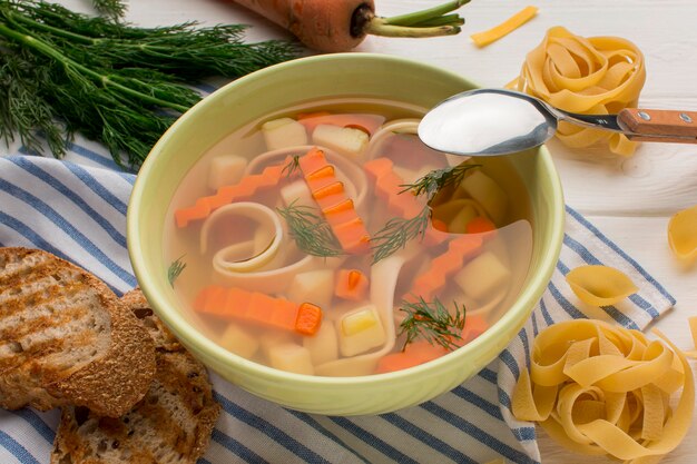 Высокий угол супа из зимних овощей в миске с ложкой и тостами