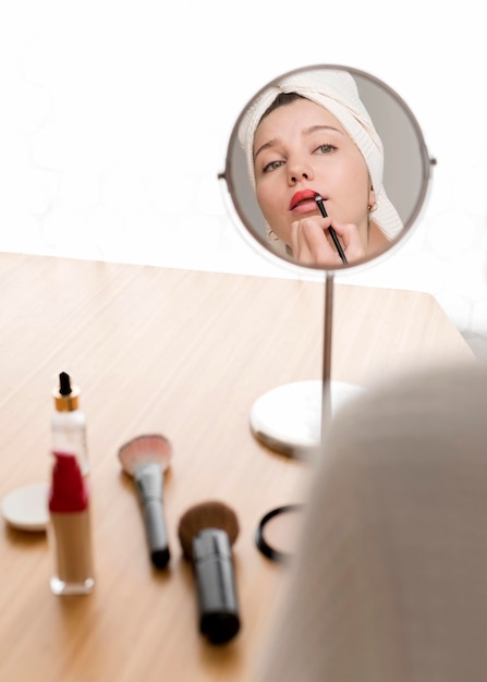 Free photo high angle woman applying lipstick