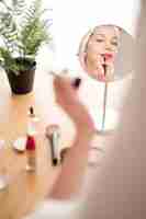 Free photo high angle woman applying lipstick