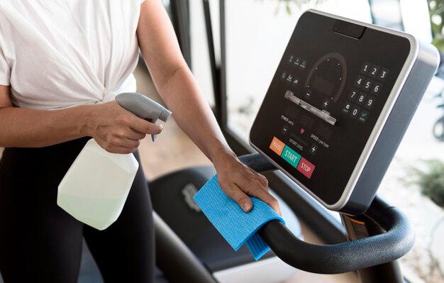 High angle of woman cleaning gym equipment