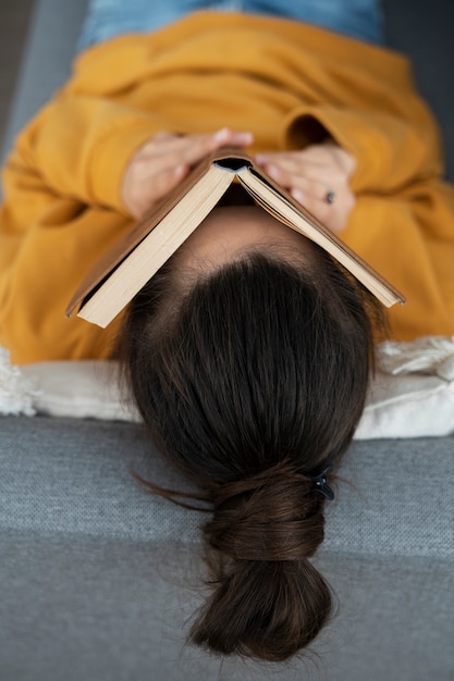 Free photo high angle woman covering face with book