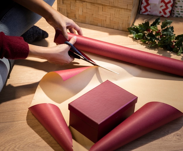 High angle woman cutting paper to wrap gifts