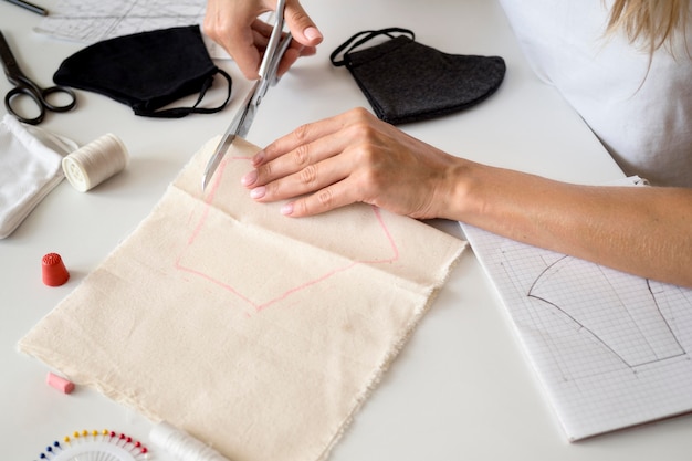 High angle of woman cutting textile to sew face mask