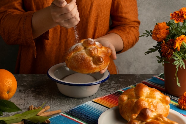 High angle of woman decorating pan de muerto with sugar