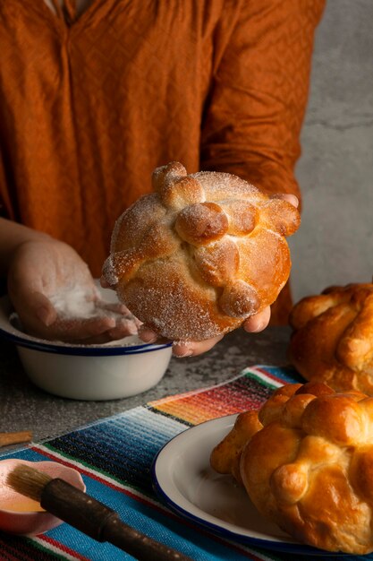 High angle of woman decorating pan de muerto with sugar