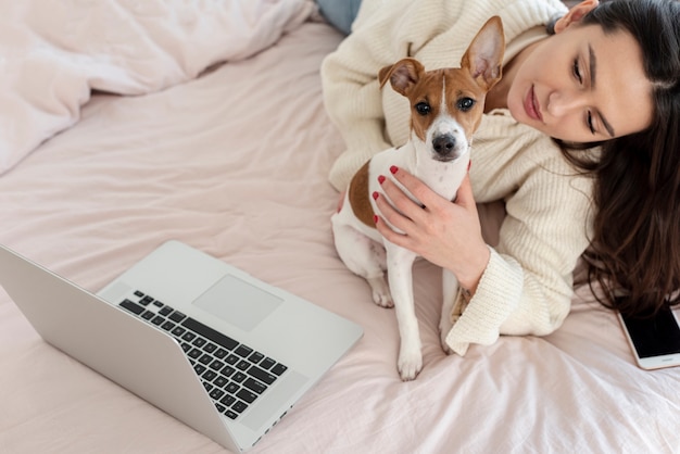 Free photo high angle of woman and dog in bed