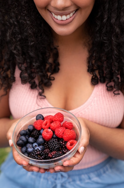 Foto gratuita donna dell'angolo alto che mangia le bacche