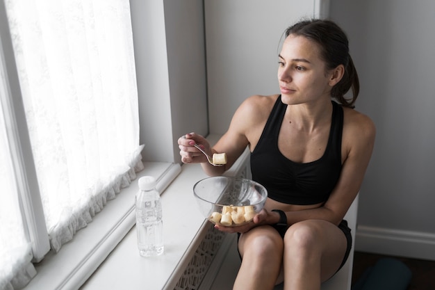 Foto gratuita angolo alto della donna che mangia pasto e che osserva attraverso la finestra