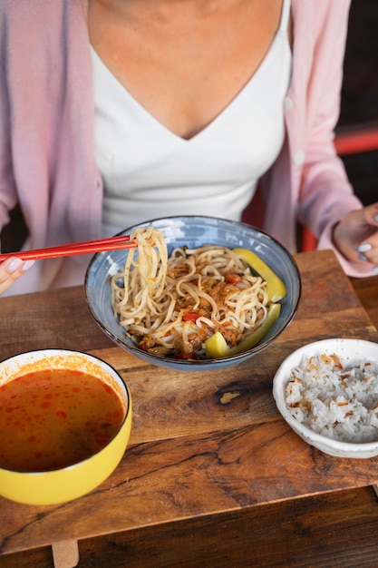 Free photo high angle woman eating with chopsticks