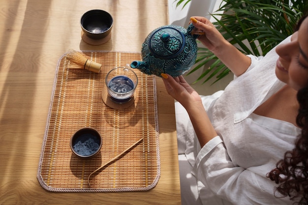 Free photo high angle woman enjoying blue matcha at home