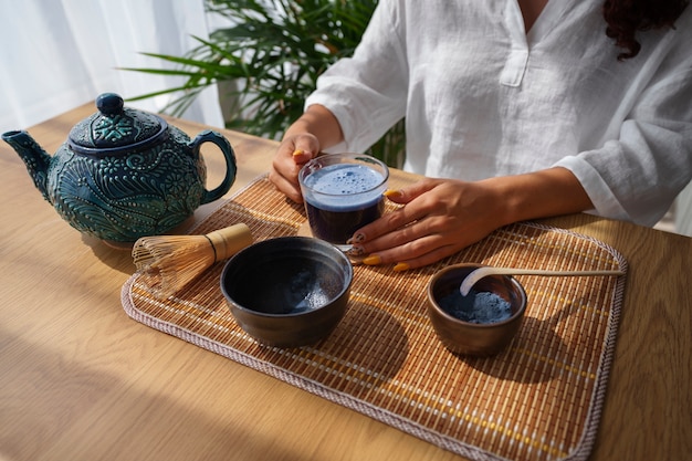 Free photo high angle woman enjoying blue matcha at home