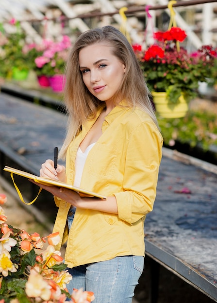 Free photo high angle woman in grenehouse writing