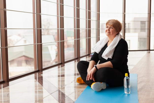 Foto gratuita donna dell'angolo alto al riposo della palestra