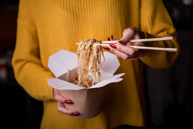 Free photo high angle of woman holding box of noodles